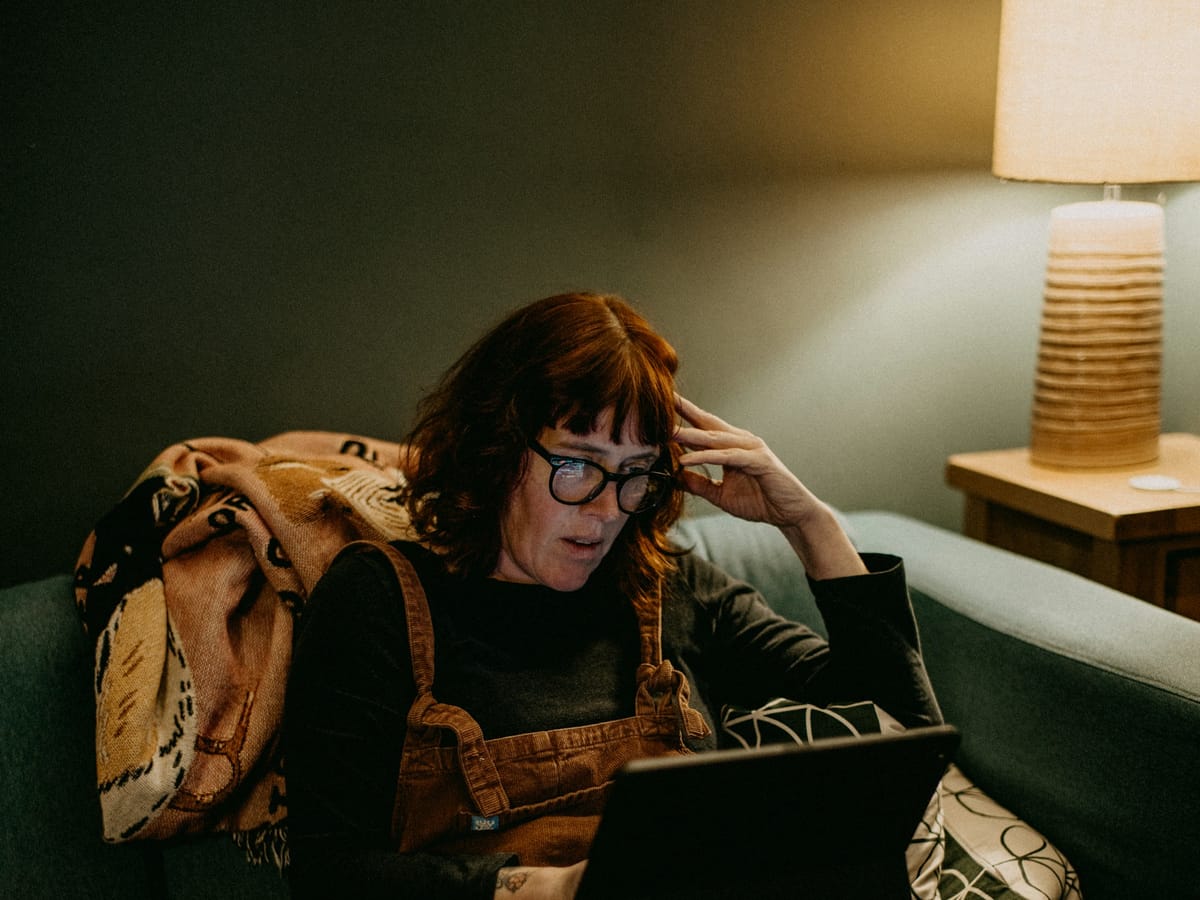 Woman on the sofa searching for an answer on her laptop in the evening