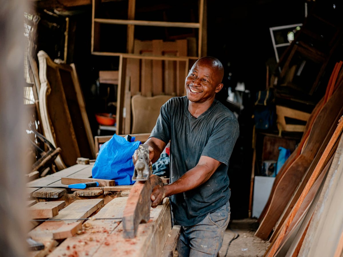 Carpenter smiling while working a board in his workshop
