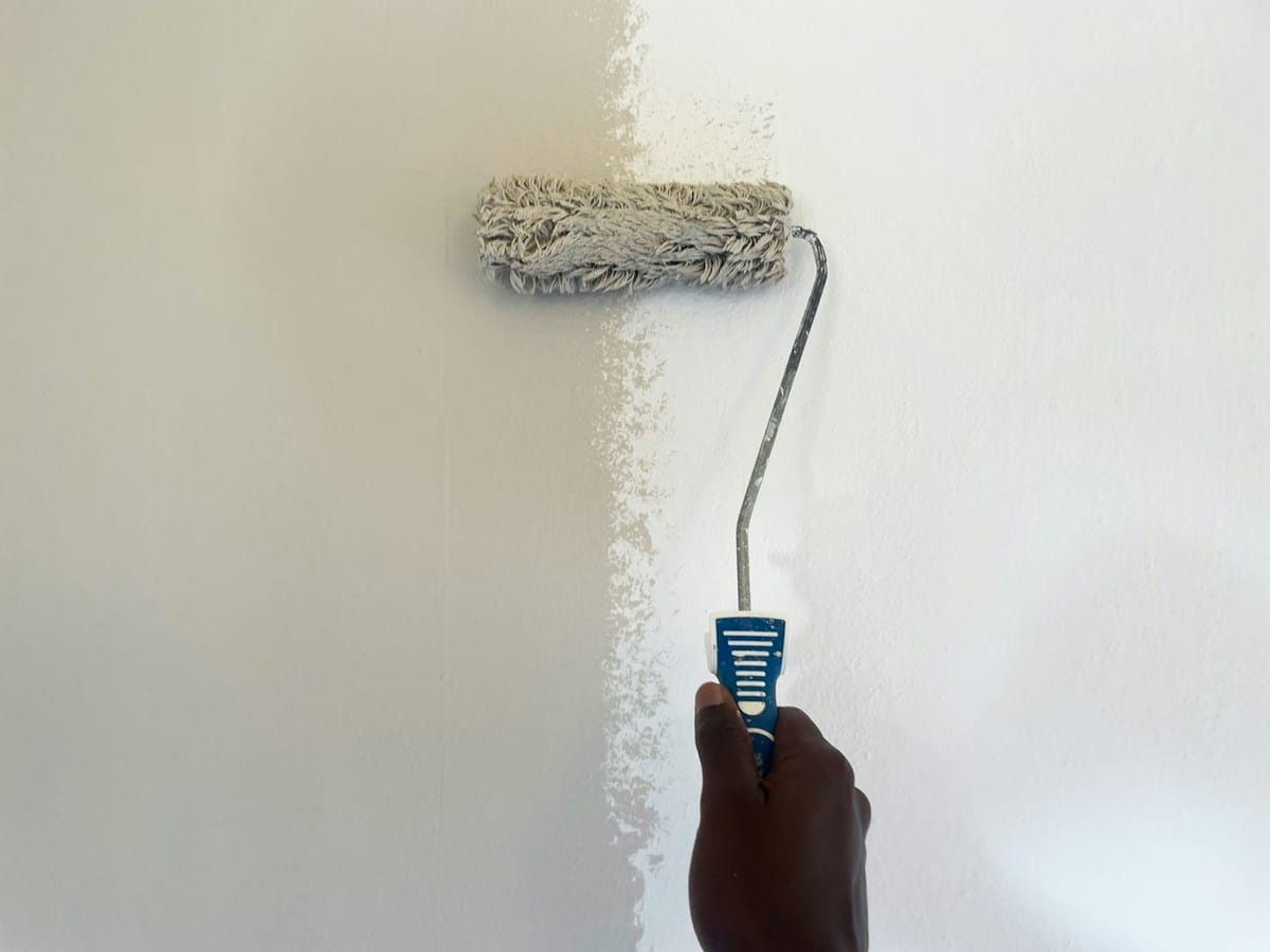 Malerrolle streicht eine Wand weiß