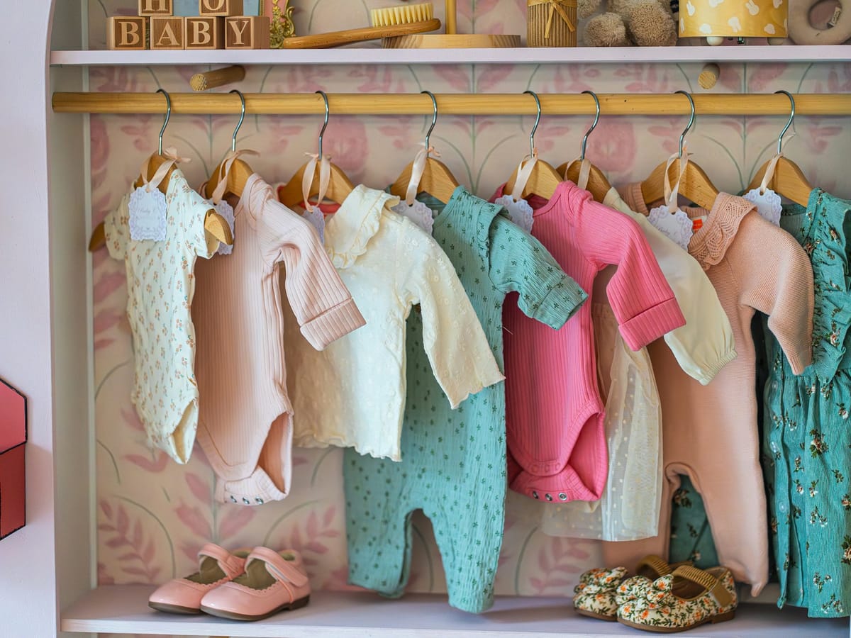 Children's clothes on hangers with small shoes below