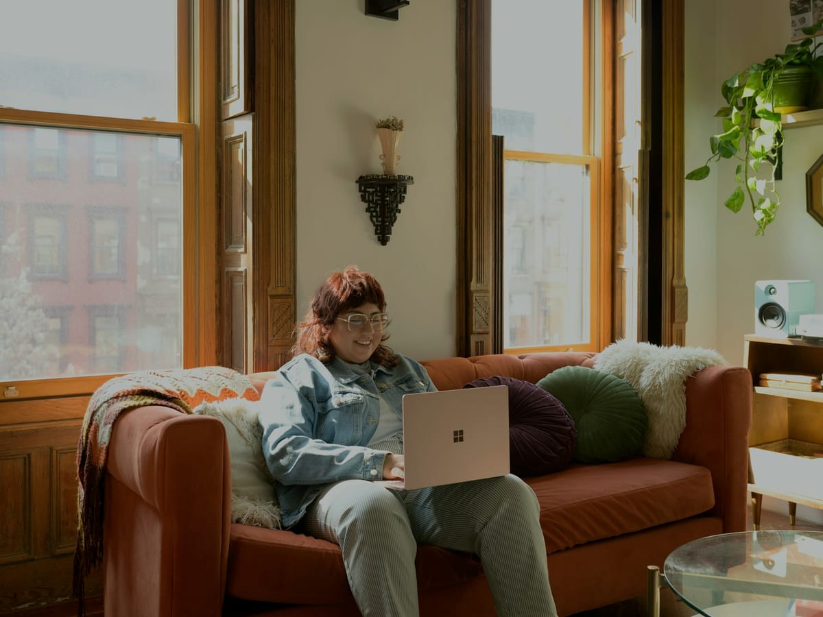 Woman sitting on a sofa with a laptop in a bright living room